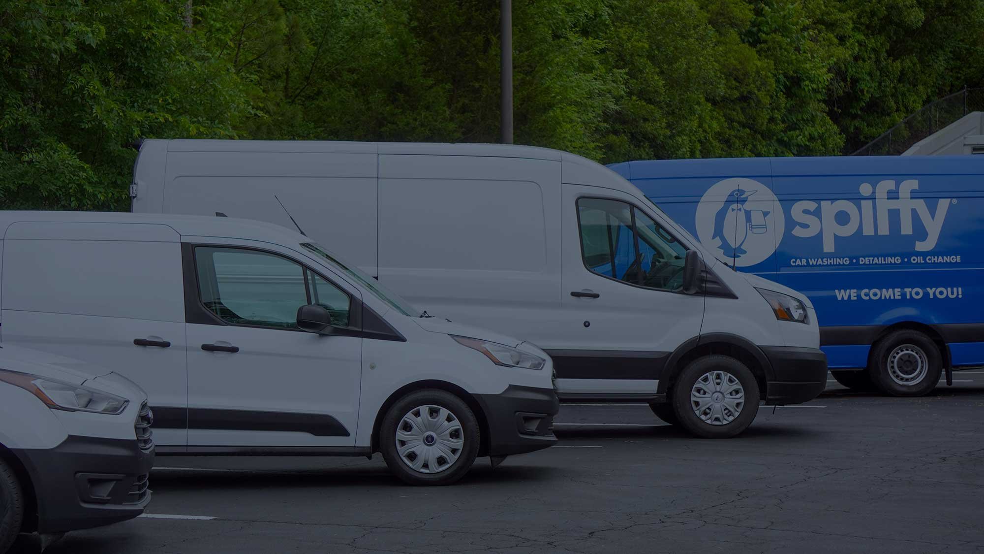 Row of white and blue fleet vans parked, ready for vehicle remarketing services