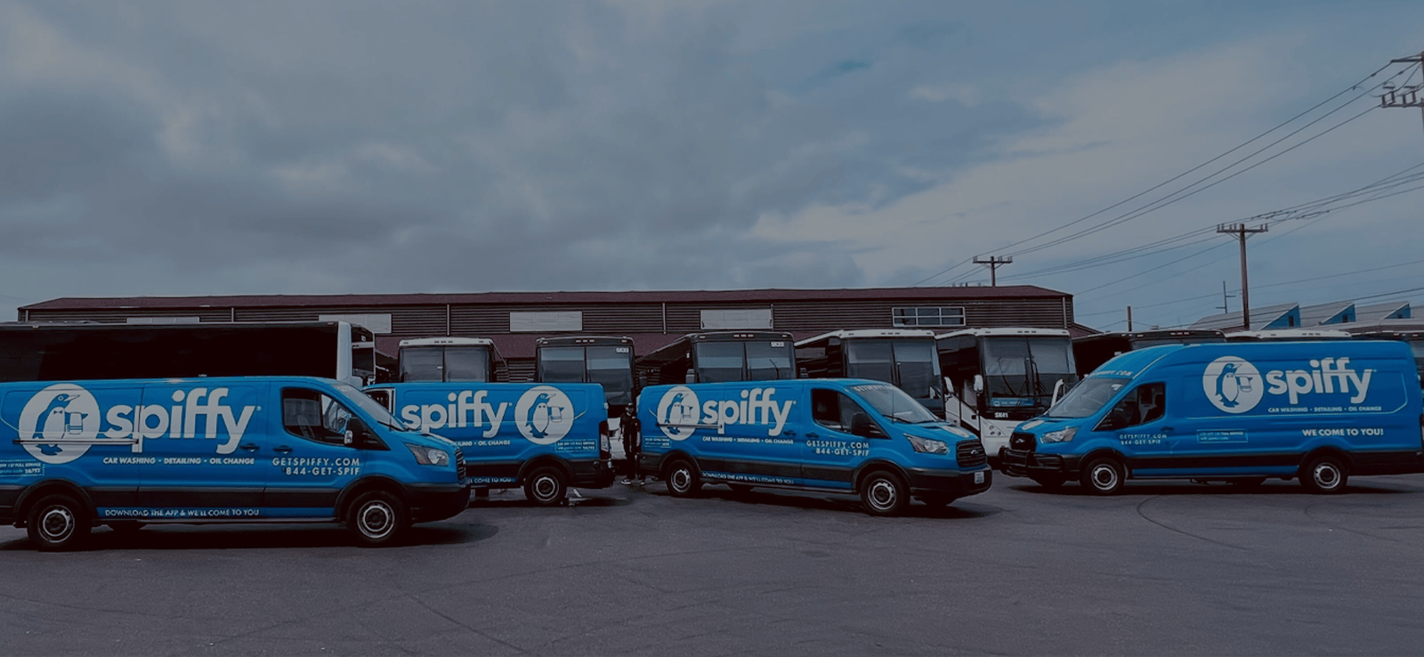 Row of blue Spiffy service vans parked in a lot