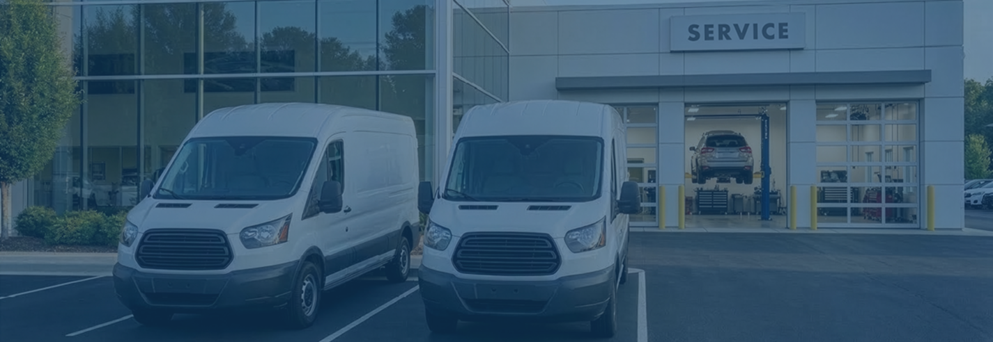 Two white Spiffy mobile service vans parked outside a dealership service center.