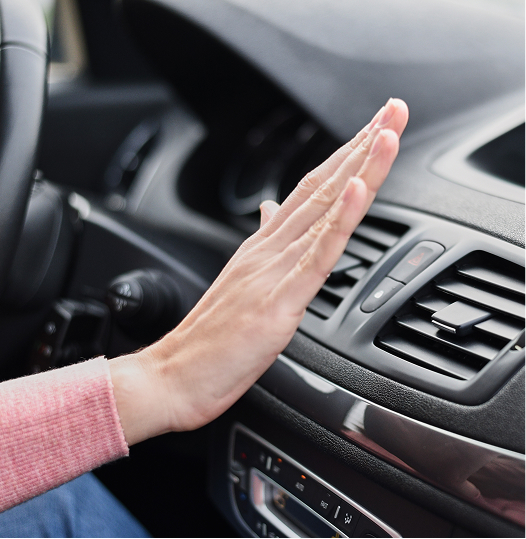 Hand feeling air flow from a vehicle's dashboard vent