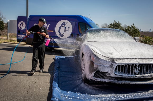 Spiffy technician at work location washing car on eco-friendly wash mat Spiffy technician at work location washing car on eco-friendly wash mat