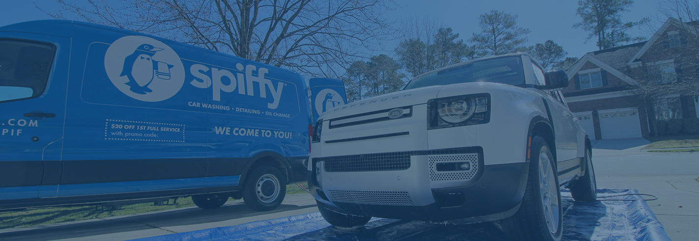 Spiffy service van parked next to a vehicle being serviced in a driveway.